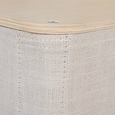 Esquina de un mueble con madera clara y tapizado beige de aspecto lino, tornillo visible en la parte superior.