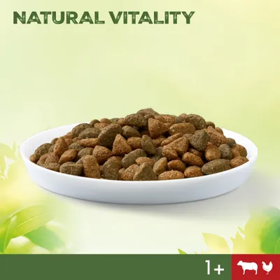 Bowl of dry pet food with text 'NATURAL VITALITY', icons for beef and chicken, and '1+' age indicator visible at the bottom right.