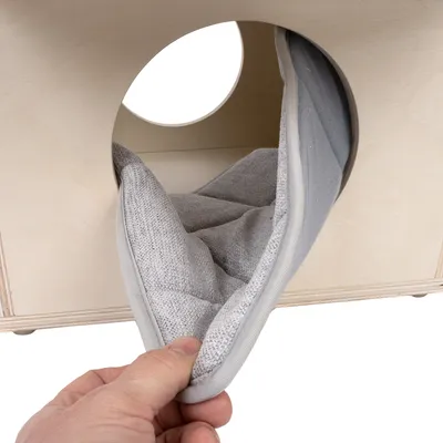 Removable grey cushion being pulled out of a wooden box with a round entrance.