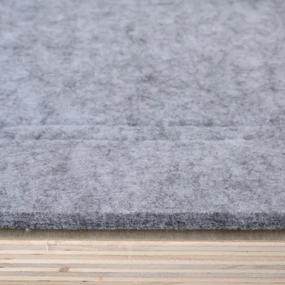 Grey felt pad on a wooden surface, close-up of material texture.