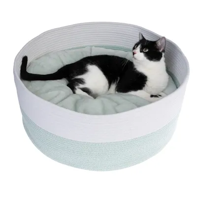 Rundes Katzenbett mit weicher Polsterung, schwarz-weisse Katze liegt darin.