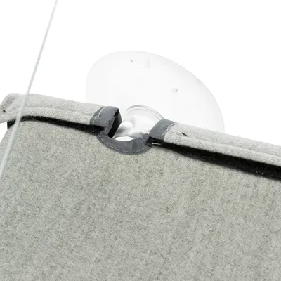 Gros plan sur une ventouse transparente fixée à un support en tissu gris, montrant le système d’attache du produit.