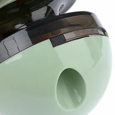 Green plastic toy with black twist cap and opening for treats.