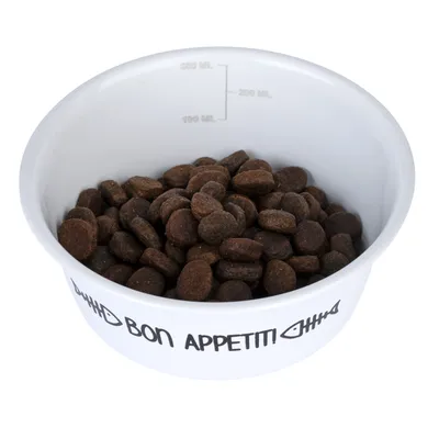 Vit matskål med texten 'Bon Appetit' och fisksymboler, fylld med bruna foderkulor. Mätskala från 100 ml till 300 ml synlig.