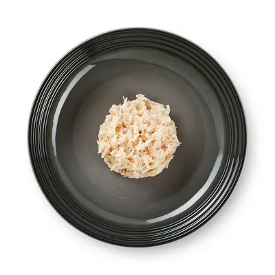 Portion of shredded light-coloured meat on a black plate, shown to illustrate the product's consistency.