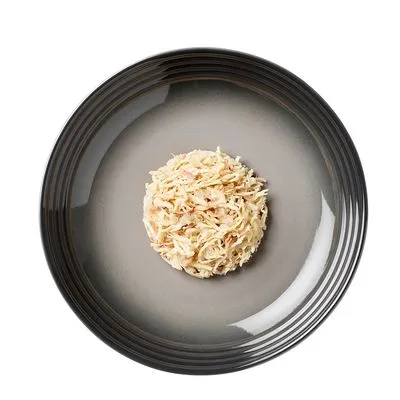 Portie natvoer met stukjes vlees op een grijs bord, bovenaanzicht. Geen merknaam of verpakking zichtbaar.