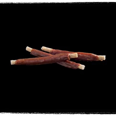 Three stick-shaped pet treats with a light centre and darker outer layer, shown on a black background.