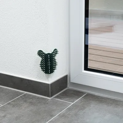 Green wall brush in corner mounting, suitable for pet grooming. Attached to a white wall next to a glass door.