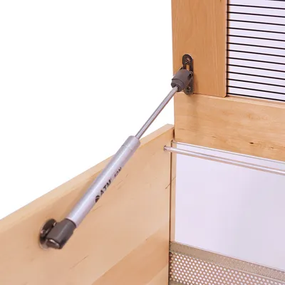 Gasdruckfeder mit Metallhalterung an einer Holztür, zeigt die Befestigung und Funktion der Türöffnung.