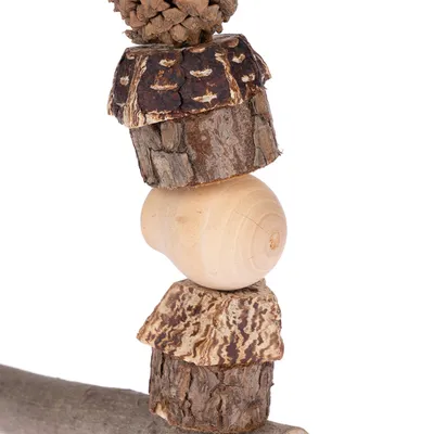 Jouet pour rongeur composé de morceaux de bois naturel, écorce et pomme de pin empilés sur une tige en bois. Matériaux visibles : bois, écorce, pomme de pin.