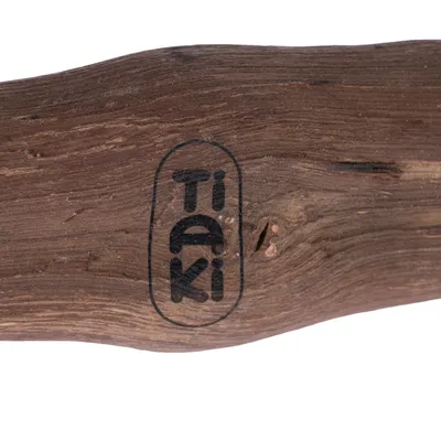 Tiaki-Logo auf einem Stück Holz, natürliche Maserung sichtbar.