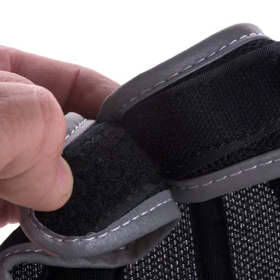 Primo piano di una chiusura a strappo su materiale grigio e nero con cuciture visibili.