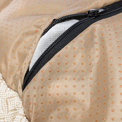 Nahaufnahme eines beige gepunkteten Stoffes mit Reißverschluss und darunterliegendem weißen Netzmaterial.