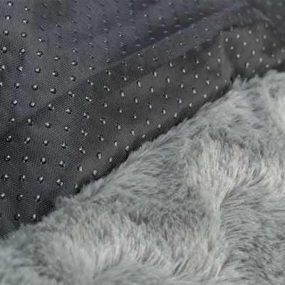 Nahaufnahme eines grauen, weichen Kunstfellmaterials neben einer schwarzen, rutschfesten Unterseite mit Noppenstruktur.