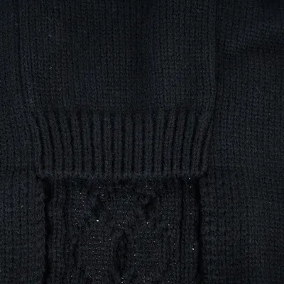 Gros plan sur un tricot noir à motif torsadé, matière textile visible.
