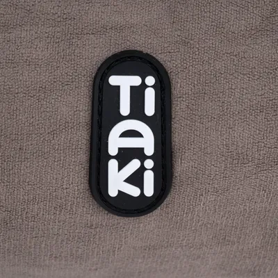 Taki. Brand logo on brown fabric background.