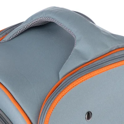 Détail d’une poignée en tissu gris avec bordure orange sur un sac ou une caisse de transport, couture visible et œillet métallique apparent.
