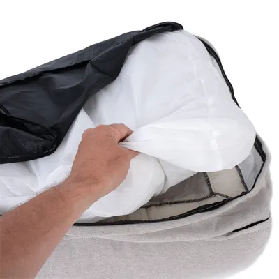 Hand showing removable cover of a pet bed with zip and removable inner cushion.