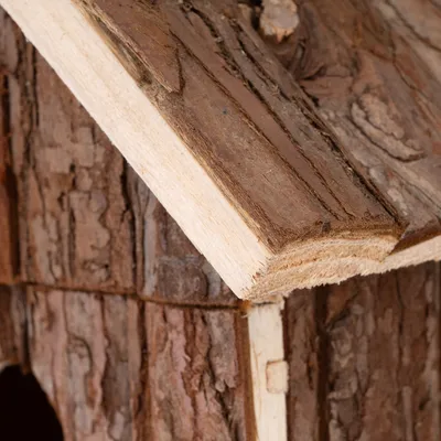 Närbild av ett trähus med naturlig barkstruktur, lämpligt för smådjur eller dekoration.