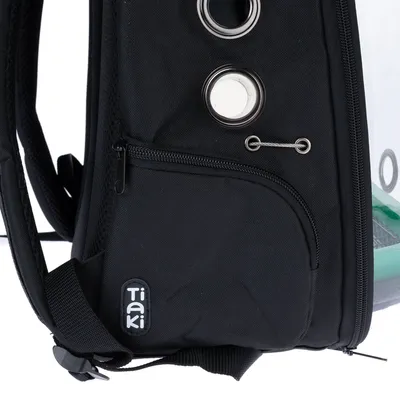 Sac noir avec poche zippée, œillets métalliques et logo visible « TIAKI » sur le côté inférieur gauche.