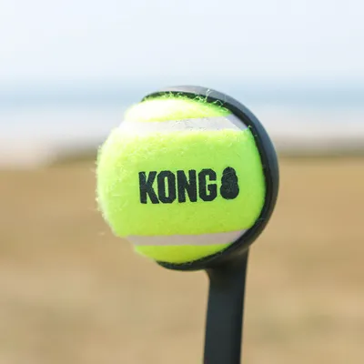 KONG tennis ball in bright yellow, attached to a black throw arm for dogs.