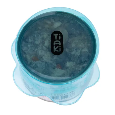 Tiaki wet food in transparent blue packaging, 180g. Visible ingredients such as meat pieces and vegetables.