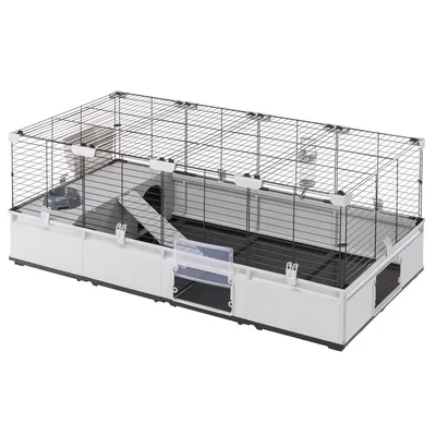 Grosses Gehege mit Metall-Gitterwänden, weissem Kunststoffboden und Rampen. Integrierte Futterstation und Zugangstür vorne sichtbar.