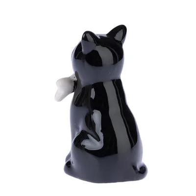 Figurine en céramique noire représentant un chat vu de dos, tenant un petit objet blanc dans la patte gauche. Aucun texte ou marque visible.