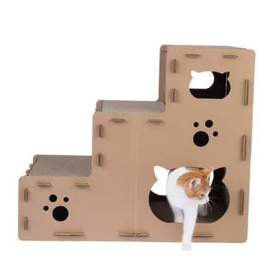 Katzenhaus aus Pappe mit drei Ebenen, Katzenkopf- und Pfoten-Ausschnitten. Weisse Katze verlässt die untere Ebene durch einen Ausschnitt.