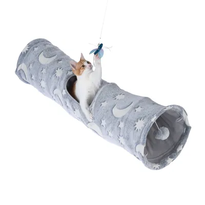 Grauer Spieltunnel mit Mond- und Sternmotiven, Katze spielt mit blauem Spielzeug an Schnur. Tunnel hat Öffnungen und hängendes Herzspielzeug innen.