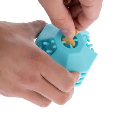 Una mano inserisce uno snack in un gioco blu con aperture a forma di spina.