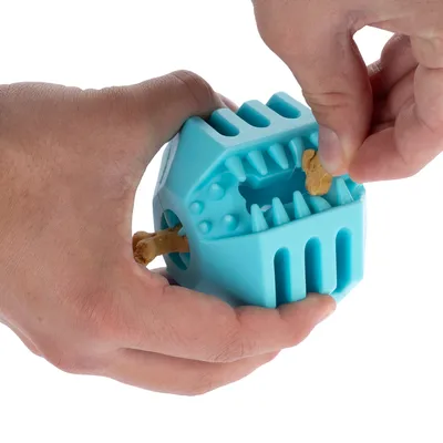 Mani riempiono un gioco blu con snack e un osso da masticare. Il gioco ha aperture e dentelli per snack.