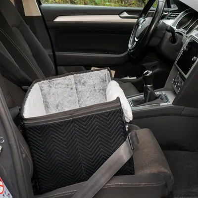 Schwarzer Autositz für Haustiere mit grauem, weichem Innenfutter, befestigt mit Sicherheitsgurt auf dem Beifahrersitz eines Autos.