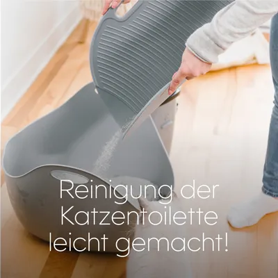 Reinigung der Katzentoilette leicht gemacht! Person leert Katzenstreu aus grauer Katzentoilette mit abnehmbarem Deckel.