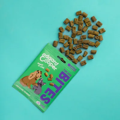 Edgard Cooper TOP DOG BITES, small in size, low calorie, 125 g. Groene verpakking met hondenillustratie en uitgestrooide bruine snacks zichtbaar.