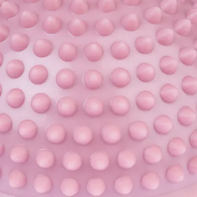 Primo piano di una superficie rosa con rilievi a forma di nodi, possibile struttura del materiale di un prodotto.