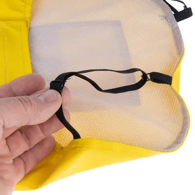 Main tenant une sangle élastique noire fixée à un tissu jaune et maille blanche, détail d’un accessoire pour animaux avec coutures visibles.