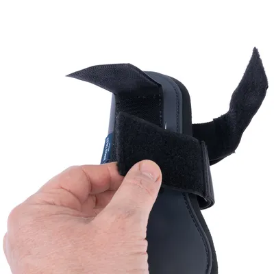 Nahaufnahme einer Hand, die einen schwarzen Klettverschluss an einem Produkt öffnet. Zeigt die Funktion des Verschlussmechanismus.