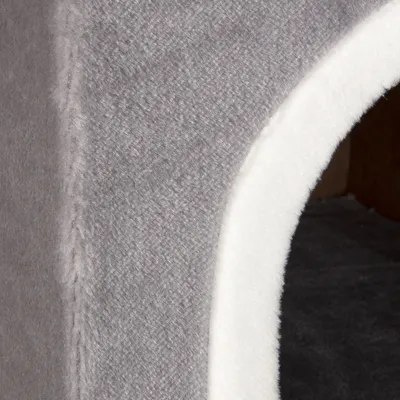 Entrée d’une niche ou maisonnette pour animal, revêtement en tissu gris et bordure blanche visible. Aucun logo ni texte apparent.