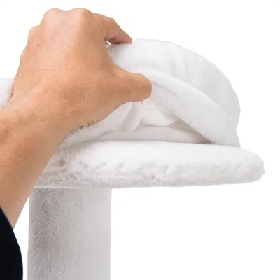 Ruka podiže bijelu plišanu navlaku s okrugle platforme, vidljiv je sloj tkanine ispod. Materijal: tkanina i pliš.