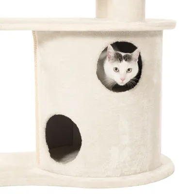 Krabpaal met beige pluche bekleding, ronde schuilplek en een witte kat met zwarte vlekken die uit het bovenste gat kijkt. Onderin extra opening zichtbaar.