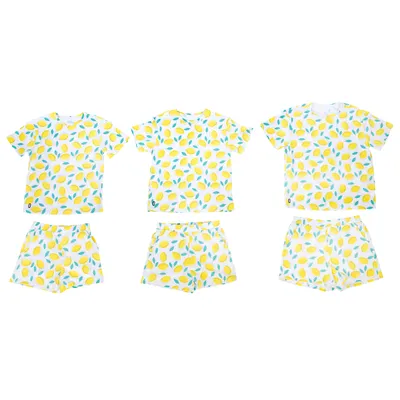 Trois ensembles t-shirt et short assortis, motif citrons jaunes et feuilles vertes sur fond blanc, présentés à plat. Aucun logo ou marque visible.