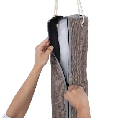 Hand öffnet Reissverschluss eines hängenden Kratzbrettbezugs aus braunem Sisal mit weisser Füllung.