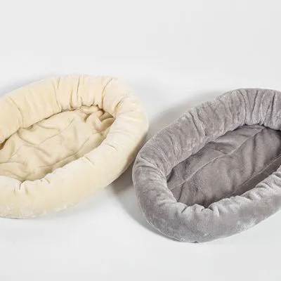 Twee ovale pluche dierenmanden, één beige en één grijs, met opstaande randen en zachte bekleding. Beide manden liggen naast elkaar op een witte achtergrond.
