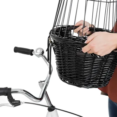 Cestino in vimini nero con griglia metallica, fissato al manubrio di una bicicletta, mani che lo tengono. Marchio CSTAR visibile sul freno.
