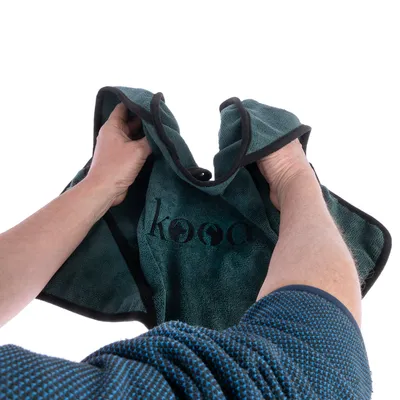 kooa Handtuch in dunkelgrün mit schwarzem Rand, von Händen gehalten. Premium-Pflegemarke für Haustiere.