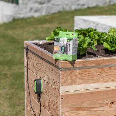 Snail Stop Schneckenschutz-System, sichtbar auf einem Hochbeet mit Salatpflanzen. Verpackung zeigt Produktdetails und Anwendungshinweise.