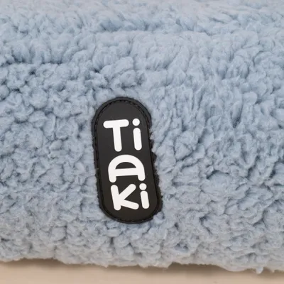 Tiaki Schriftzug auf hellblauem, flauschigem Stoff.