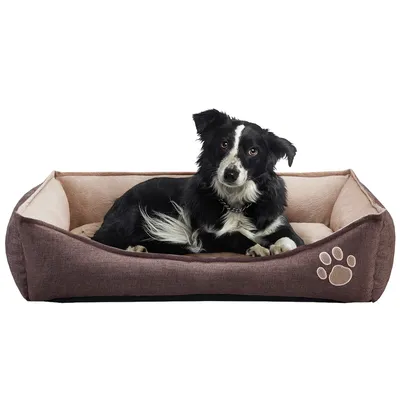Zwart-witte hond liggend in rechthoekig hondenbed van stof met opstaande randen en pootafdrukmotief aan de voorkant.