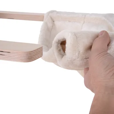 Hand showing removable, soft cover made of cream-coloured fabric on a wooden platform.